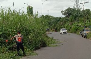 Personel Polsek Jejawi Bersihkan Ilalang yang Hampir Menutupi Jalan Desa Karang Agung